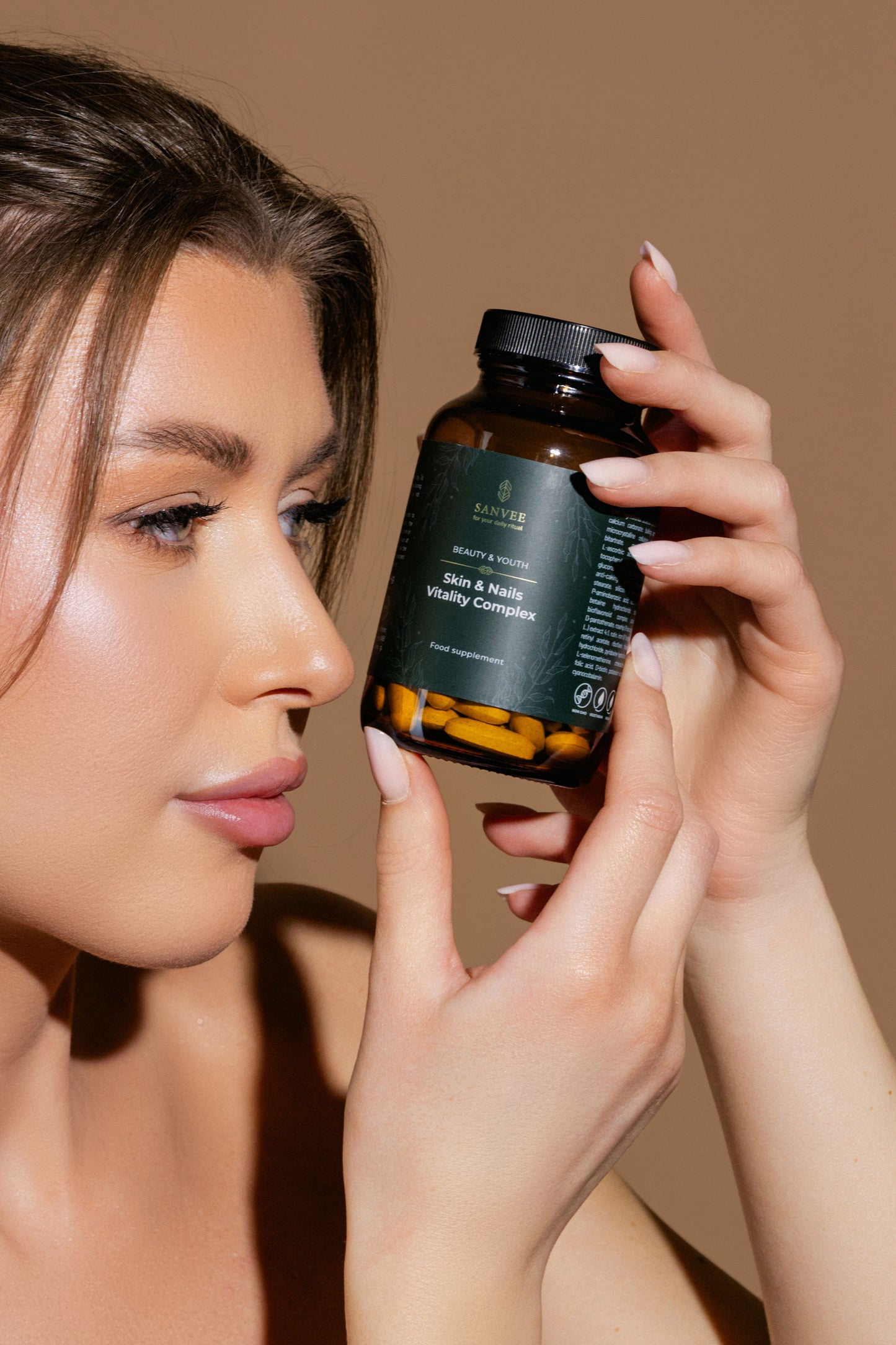 Woman holding Sanvee skin and nails vitality complex bottle near face