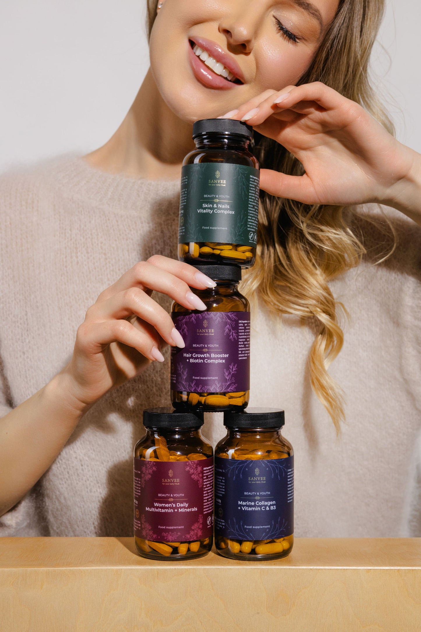 Woman holding Sanvee supplement bundle including hair growth biotin complex skin and nails vitamins collagen and multivitamin