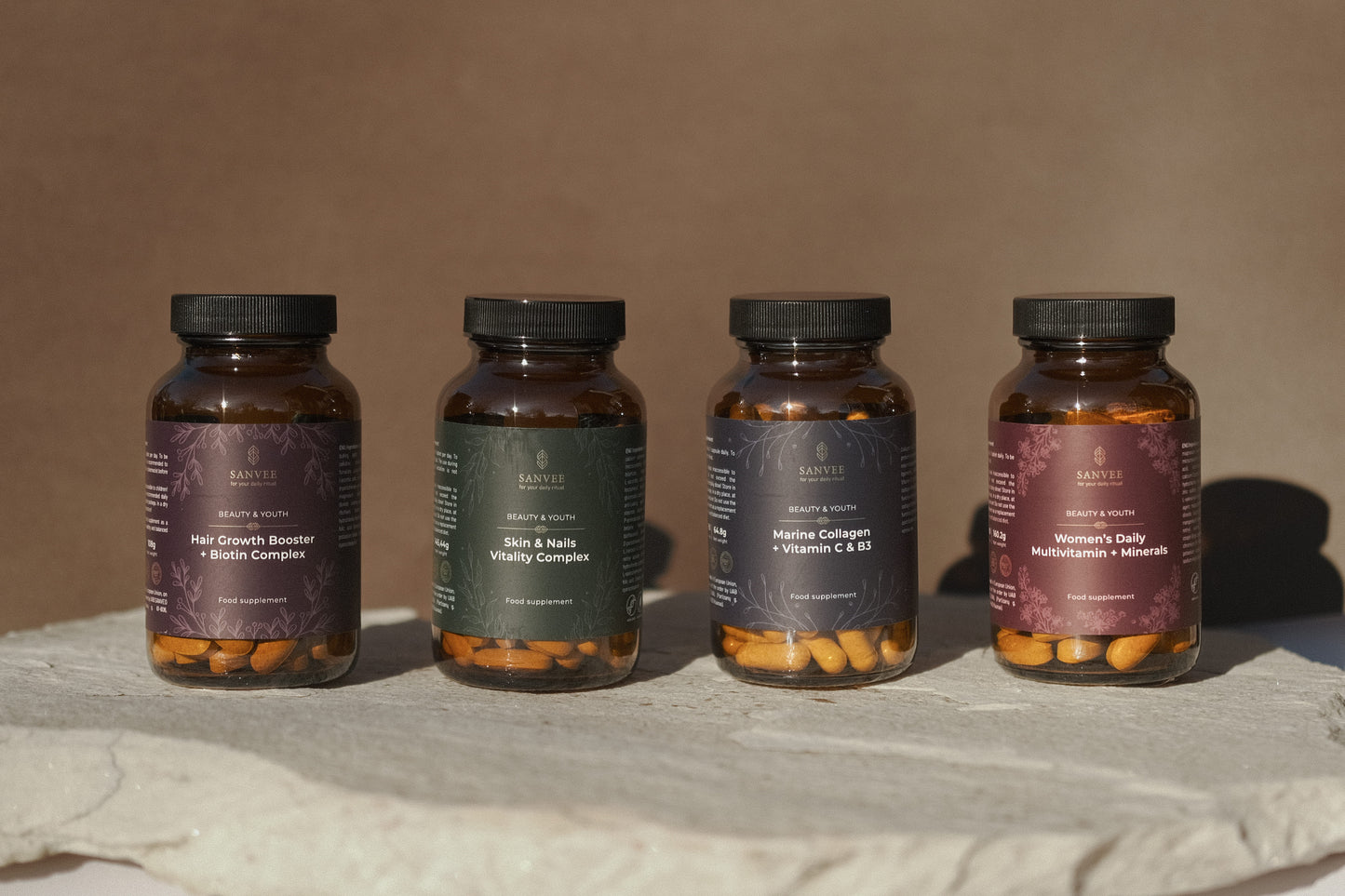 Sanvee supplement collection including hair growth biotin skin and nails collagen and multivitamin bottles on stone surface