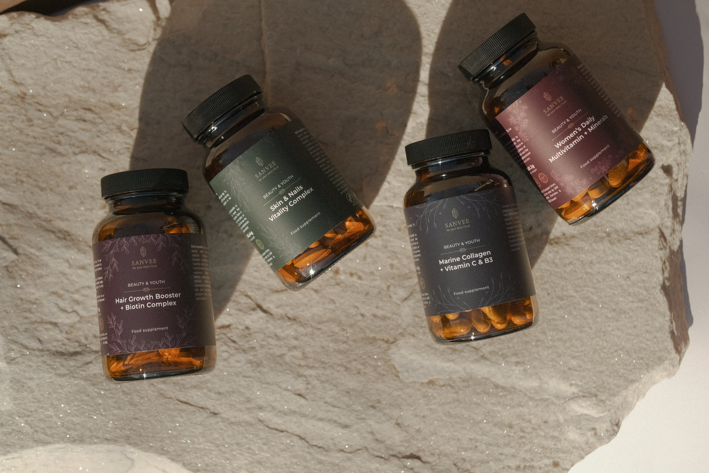 Sanvee supplement collection including hair growth biotin skin and nails collagen and multivitamin bottles arranged on natural stone