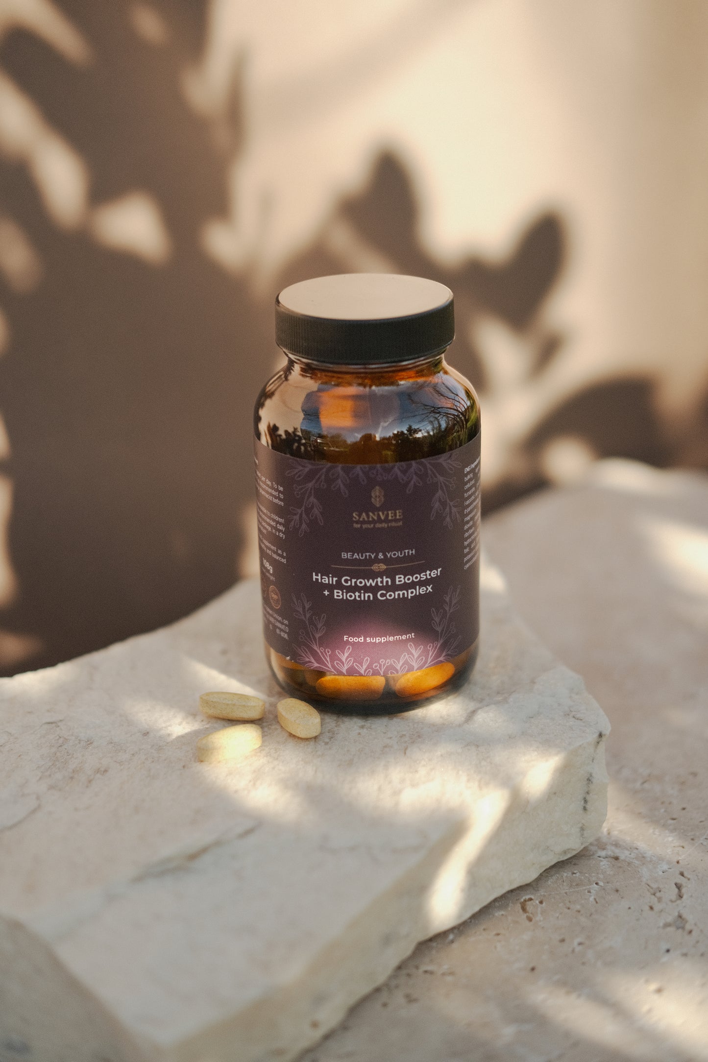 Sanvee hair growth booster with biotin bottle with tablets on stone surface
